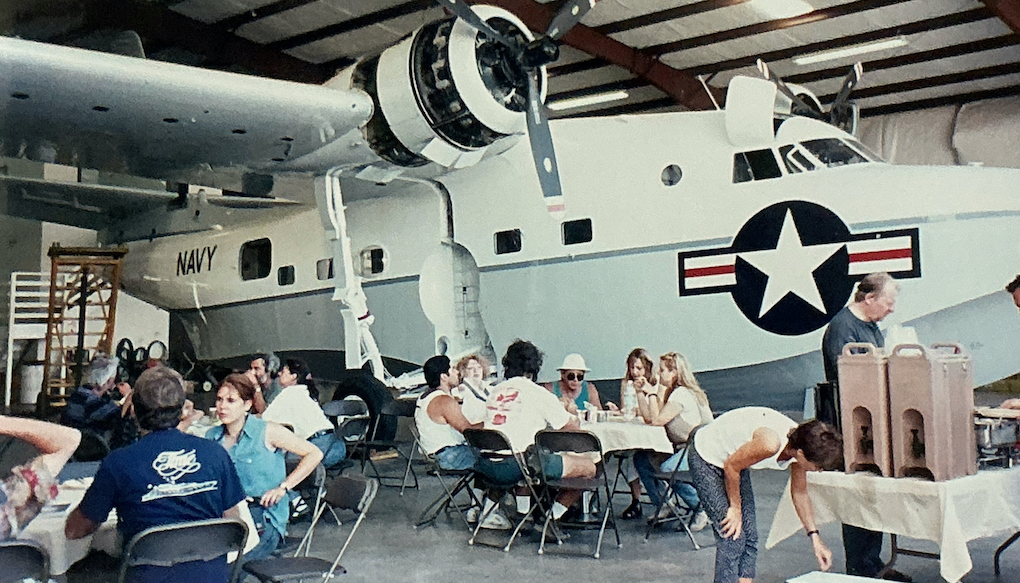 Die Crew an Tischen im Hangar neben einem Flugzeug